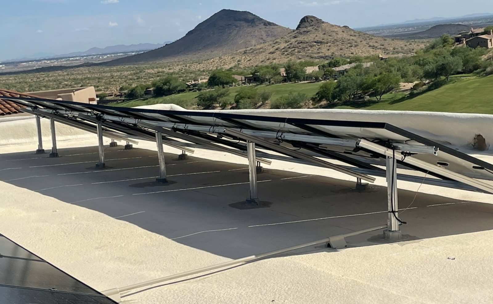 Tilted solar racking on a flat roof with desert mountains behind