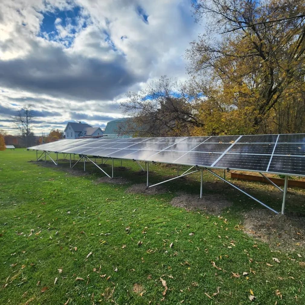 A long ground-mounted solar array in a yard in autumn
